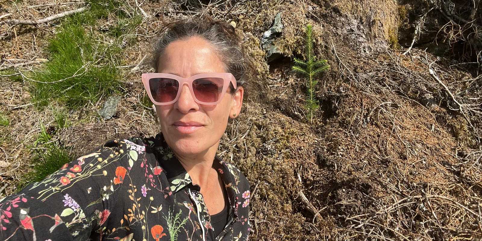 Katy Chada stands in the forest, looking into the camera.