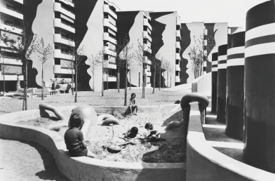 Schwarz-weiss-Bild der Wohnüberbauung Heuried, mit spielenden Kindern im Sandkasten im Vordergrund.